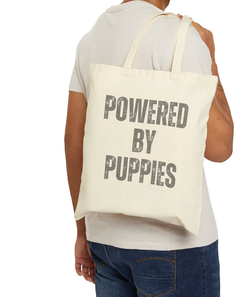 ﻿Unleash the joy with our "Powered by Puppies" tote bag! 🐾 Carry a daily dose of happiness, recharge your spirits, and let the world know that your energy source is the magic of puppy power 🐶