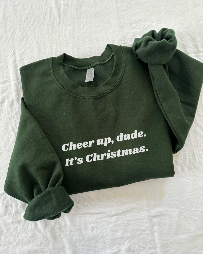 Elevate your holiday spirit with our "Cheer Up, Dude" Sweatshirt. This cozy essential features a fuzzy soft interior that's perfect for staying warm and comfortable during the festive season. With unisex sizing and ribbed knit details, it's a versatile and stylish addition to your winter wardrobe. Spread cheer and laughter with a touch of holiday humor – 'tis the season to be jolly, after all. Get ready to embrace the joy and stay toasty in style with this must-have sweatshirt.