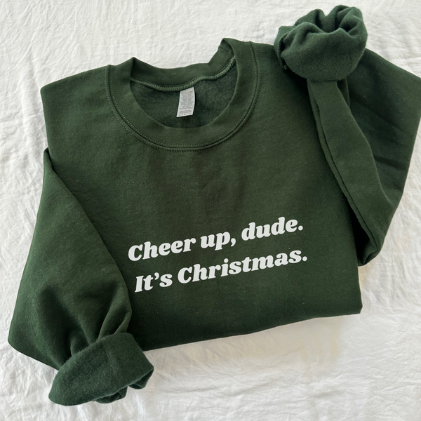 Elevate your holiday spirit with our "Cheer Up, Dude" Sweatshirt. This cozy essential features a fuzzy soft interior that's perfect for staying warm and comfortable during the festive season. With unisex sizing and ribbed knit details, it's a versatile and stylish addition to your winter wardrobe. Spread cheer and laughter with a touch of holiday humor – 'tis the season to be jolly, after all. Get ready to embrace the joy and stay toasty in style with this must-have sweatshirt.
